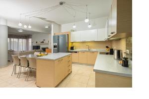 a kitchen with white cabinets and a kitchen island with chairs at Beach Bar VIlla in Lefkada