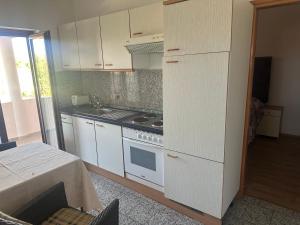 a kitchen with white cabinets and a stove top oven at Apartments Ava in Babići