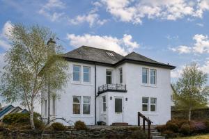 a white house with a balcony on top of it at Drumornie in Brora