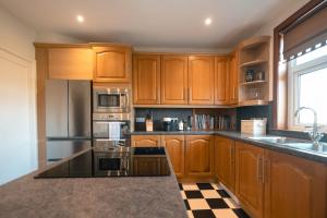 a kitchen with wooden cabinets and stainless steel appliances at Drumornie in Brora