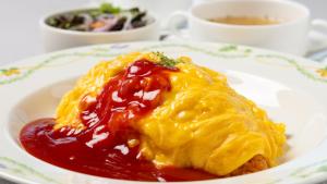 a plate of food with a pile of eggs and sauce at ホテルドゥアッシュ in Kushiro