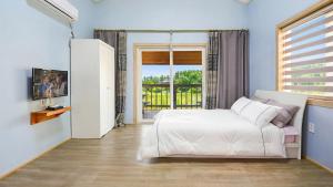 a bedroom with a white bed and a large window at Samcheok Good Friend Pension in Samcheok
