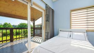a bedroom with a bed and a balcony at Samcheok Good Friend Pension in Samcheok