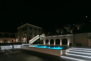 a swimming pool at night with a building in the background at Vinea Relais in Dogliani