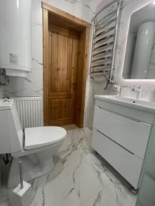 a white bathroom with a toilet and a sink at InMonteHouse in Migovo