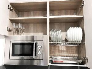 a kitchen with a microwave and some plates and wine glasses at Studio Alborán in Málaga +43 photos