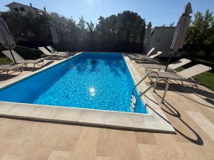 a swimming pool with lounge chairs and a pool at My House in Paralia Messi in Aroyí