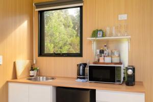 a kitchen with a counter with a microwave and a window at The Wollombi Wanderer by Tiny Away in Wollombi