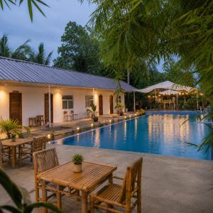 a pool with tables and chairs next to a resort at Sunset Villas Palauig Zambales in Palauig