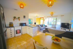 a living room with a kitchen and a table with a bowl of fruit at NR 4 Cove Apartment Carrickalinga in Carrickalinga
