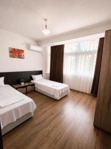 a hotel room with two beds and a window at Alex City Apartment Gabrovo in Gabrovo