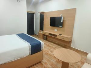 a bedroom with a bed and a tv and a table at Hotel Shiny Grand in Guwahati