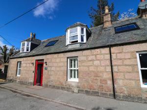 an old brick house with a red door at Evansford in Ballater