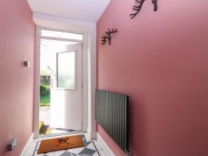a hallway with a pink wall and a doorway at Evansford in Ballater