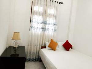 a white bedroom with a bed and a window at Ciao Villa, Kandy in Kandy