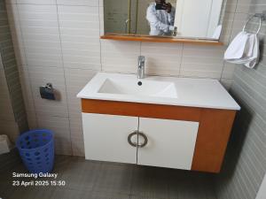 a bathroom with a white sink and a mirror at La Maison Mara in Ololaimutiek