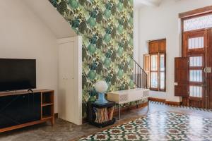 a living room with a tv and a wall at La Casona Beach House in Valencia
