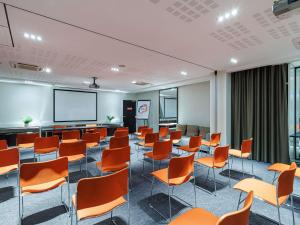 a conference room with orange chairs and a projection screen at Adagio Nice Centre in Nice