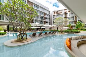 a swimming pool with chairs and umbrellas in a building at Radisson Resort Layan Phuket in Layan Beach