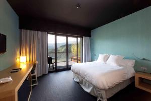 a hotel room with a bed and a desk and a window at Grupo Izarbe, HOTEL ELLAURI in Zeanuri