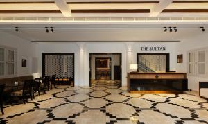 una hall con un pianoforte, un tavolo e delle sedie di The Sultan a Singapore