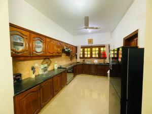 a kitchen with wooden cabinets and a black refrigerator at Signature 3 Bed Villa Clifton Boat Basin in Karachi
