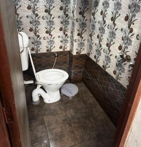 a bathroom with a toilet and a wall paper at Gokul Bhawan in Kedārnāth