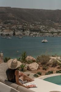 a woman in a straw hat sitting on a chair by a pool at Eunoia Suites in Krotiri +39 photos