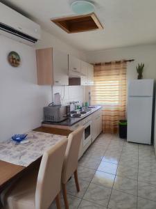 a kitchen with a table and a white refrigerator at Apartman Olja in Pag +12 photos