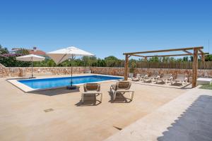 a swimming pool with lounge chairs and an umbrella at VILLA JESSELLA in Punta Prima
