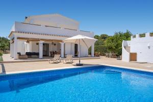 a villa with a swimming pool in front of a house at VILLA JESSELLA in Punta Prima
