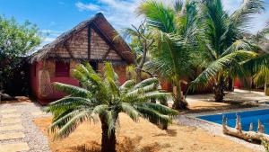 a house with a palm tree next to a swimming pool at Le Trou Normand in Antsiranana