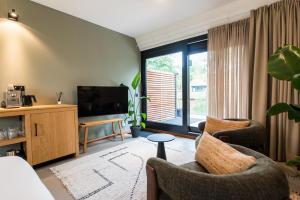 a living room with two chairs and a flat screen tv at Van Heeckeren City Centre Jacuzzi Lofts in Nes
