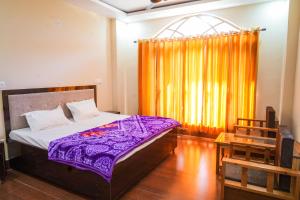a bedroom with a bed with purple sheets and a window at The Kalindi's Resort, Almora in Almora
