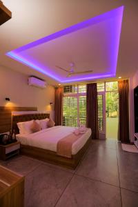 a bedroom with a large bed with a purple lighting at Adrivana Hospitality By The Stream in Padinjarathara