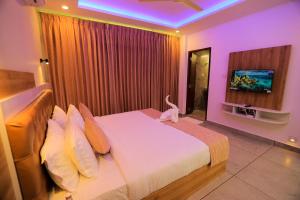 a bedroom with a large bed and a tv at Adrivana Hospitality By The Stream in Padinjarathara