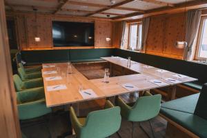 a dining room with a long table and green chairs at Hotel Enzian - Adults Only in Obertauern +92 photos