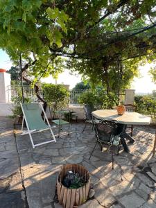 a patio with a table and chairs under a tree at The Stone House in Maronia