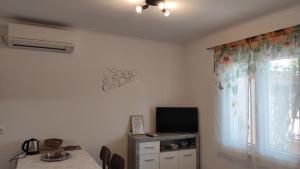 a room with a table and a television and a window at Apartman Iva in Kaštela