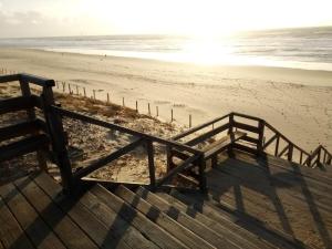 a stairway leading to a beach with the sun setting at Le Carrefour des Landes in Mimizan-Plage