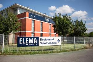 a sign on a fence in front of a building at Elema Hotels Beauvais ex Hostellerie Saint Vincent Beauvais Aeroport in Beauvais