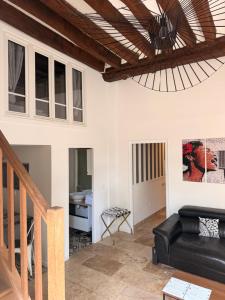 a living room with a black couch and a wooden ceiling at Studio duplex avec spa et cour privée in Bonnelles
