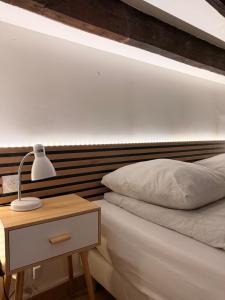 a bed with a wooden headboard and a table with a lamp at Studio duplex avec spa et cour privée in Bonnelles