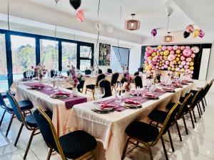 a large banquet room with long tables and chairs at H & H Boutique & SPA in Roodepoort +74 photos