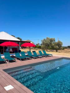 a group of chairs and umbrellas next to a swimming pool at Monte da Charnequinha Velha in Cercal