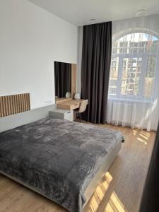 a bedroom with a bed and a desk and a window at Апарт-готель номер 303 in Truskavets
