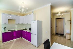 a kitchen with purple cabinets and a white refrigerator at Apartments Promenade Expo in Astana