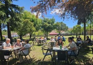 a group of people sitting at tables in a park at Hostal Restaurante Las Cavenes Del Cabaco in El Cabaco