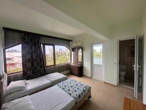a bedroom with a bed and two windows and a toilet at Hotel ARARAT in Gonio