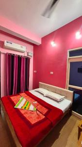 a bedroom with a bed with a red wall at Hotel Ashirwad in Chhatarpur